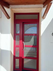 una puerta roja con una ventana en una casa en La casetta, en Pomarico