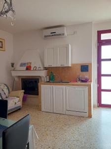 a kitchen with white cabinets and a living room at La casetta in Pomarico
