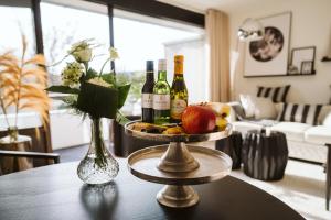 Appartement De Torenhoeve NIEUW في برغ هالمستاد: طاولة عليها زجاجات من النبيذ والتفاح