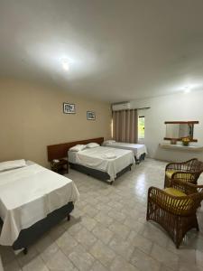a hotel room with two beds and a chair at Eldorado Inn in Feira de Santana