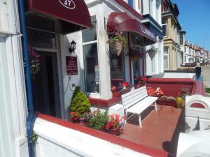 a bench in front of a store with flowers in the window at Llanryan Guest House in Blackpool