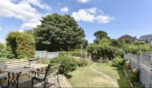 um jardim com uma mesa de madeira e bancos em Solent Sea View beach Cottage em Hill Head