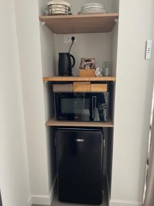 a small kitchen with a black microwave on a shelf at Chambre privatisée L’Ermitage vue sur la mayenne in Château-Gontier