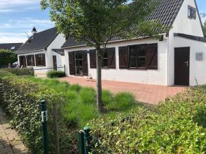 une maison blanche avec un arbre devant dans l'établissement vakantiehuis nieuwendamme, à Nieuport 2 autres photos