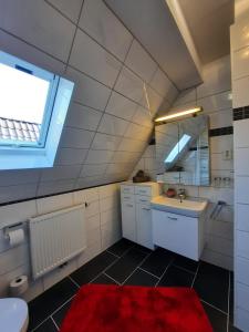 a bathroom with a sink and a red rug at Ferienwohnung Mühlennest in Emden