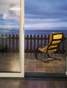 a yellow chair on a balcony with a view of the ocean at Breathe Nature - Beach House Azores in Feteira