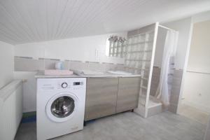 una lavanderia con lavatrice e lavandino di Gîte les Mimosas des orgues de la Sybille a Ille-sur-Têt