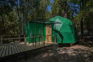 une tente verte assise sur une terrasse en bois dans l'établissement Cabañas Ensenada Bosque Nativo, à La Ensenada