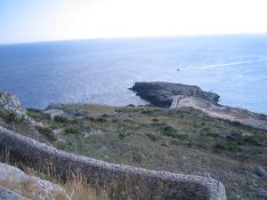 eine Steinwand auf einem Hügel neben dem Meer in der Unterkunft Lu Rusciu De Lu Vientu in Castrignano del Capo