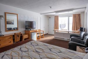 une chambre d'hôtel avec un lit, une chaise et une télévision dans l'établissement Hôtel Les Mouettes, à Sept-Îles
