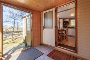 a screened in porch with a door leading to a kitchen at Beechcroft - Norfolk Cottage Agency in Holt