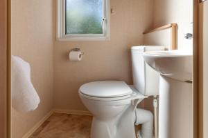 a bathroom with a toilet and a sink and a window at Beechcroft - Norfolk Cottage Agency in Holt +19 photos