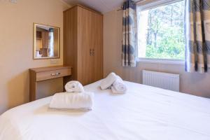 a bedroom with towels on a bed with a window at Beechcroft - Norfolk Cottage Agency in Holt