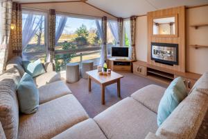 a living room with a couch and a tv at Beechcroft - Norfolk Cottage Agency in Holt