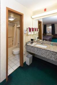 y baño con lavabo, aseo y espejo. en Express Inn Eureka Springs en Eureka Springs