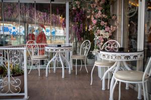 a group of white tables and chairs in front of a store at Garni Hotel Lotos in Niš