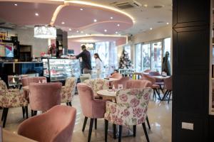 een restaurant met stoelen en tafels en een persoon op de achtergrond bij Garni Hotel Lotos in Niš