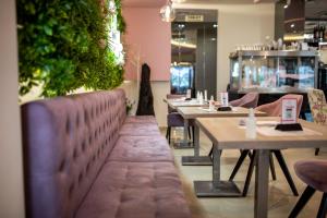 a restaurant with tables and chairs and a bench at Garni Hotel Lotos in Niš