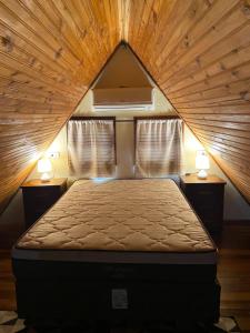 ein Schlafzimmer mit einem Bett in einer Holzdecke in der Unterkunft Chalé Bela Vista in Areias