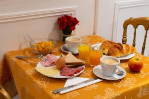 una mesa con comida para el desayuno y bebidas en ella en Hôtel Princesse Isabelle en Puteaux