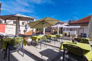 a patio with tables and chairs and umbrellas at Vila Liza in Trogir