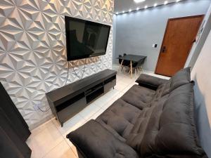 Il comprend un salon doté d'un canapé et d'une télévision à écran plat. dans l'établissement Apto Luxo Praia Grande 50m da Praia WI-FI Familiar, à Praia Grande