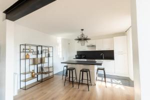 uma cozinha com armários brancos e um balcão com bancos em Villa des Arts em Épernay