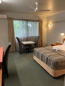a hotel room with a bed and a table and chairs at Cannon Park Motel in Cairns