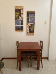 a wooden table and chairs in a room with paintings at Habitacion Independiente in Guayaquil