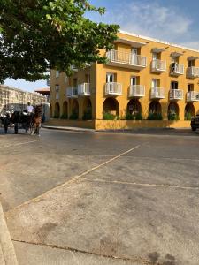 a parking lot in front of a yellow building at Happy tours apartments in Cartagena de Indias