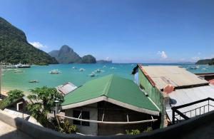 a building with a green roof next to a body of water at Happiness Hostel El Nido in El Nido