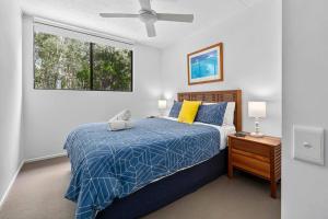 a bedroom with a bed with a blue comforter and a window at Your place. Enjoy the beach retreat in Rainbow Beach