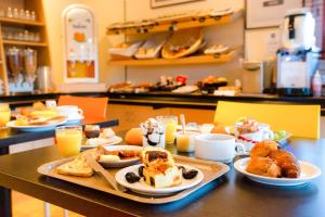 - une table avec un plateau de viennoiseries et des aliments pour le petit-déjeuner dans l'établissement Kyriad Quimper - Pont-l'Abbé, à Pont-lʼAbbé