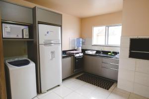 a small kitchen with a refrigerator and a sink at Morada do Mar Aberto - 100 metros da praia in Palhoça