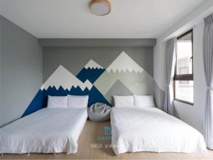 2 camas en una habitación con un mural de montaña en la pared en Muco Muco Bnb, en Yilan City