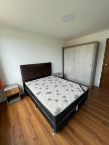 a bed in a room with a wooden floor at Edificio Flores in Piriápolis