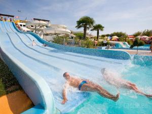 twee mensen glijden van een waterglijbaan bij een waterpark bij Home situated not far beach in Torre di Fine