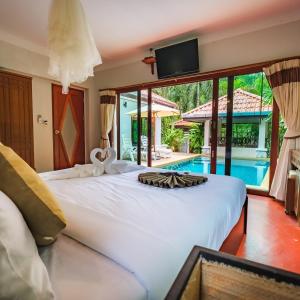 ein Schlafzimmer mit einem großen weißen Bett und einem Pool in der Unterkunft Khanom Sea Beach Resort in Nakhon Si Thammarat + 25 Fotos