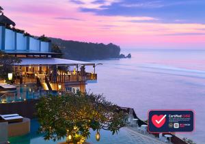 a building with a view of the ocean at sunset at Anantara Uluwatu Bali Resort in Uluwatu