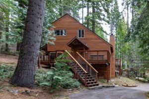 a large wooden cabin in the woods with a tree at Yosemite Silvertip Lodge in Fish Camp