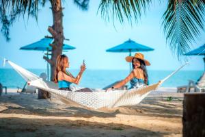 zwei Frauen sitzen in einer Hängematte am Strand in der Unterkunft Khanom Sea Beach Resort in Nakhon Si Thammarat