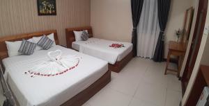 two beds in a hotel room with flowers on them at Co Ba Vung Tau Hotel in Vung Tau