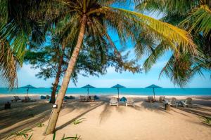 una playa con sillas y sombrillas y el océano en Khanom Sea Beach Resort, en Nakhon Si Thammarat