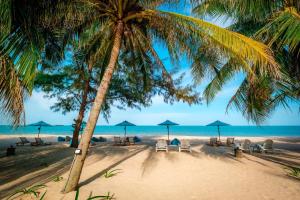 ein Strand mit Stühlen und Sonnenschirmen und das Meer in der Unterkunft Khanom Sea Beach Resort in Nakhon Si Thammarat