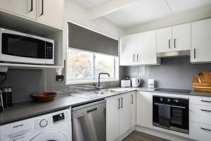 a white kitchen with a sink and a dishwasher at The HardyOne - Aldinga Beach - C21 SouthCoast Holidays in Aldinga Beach