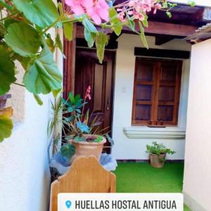 una casa con una puerta y algunas plantas y flores en Huellas Hostal Antigua, en Antigua Guatemala