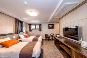 um quarto de hotel com duas camas e uma televisão de ecrã plano em Index Hotel J Dream Jeju em Jeju
