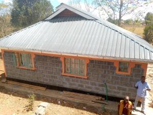 a small brick house with two people standing in front of it at Sipili Village Residence in Nyahururu