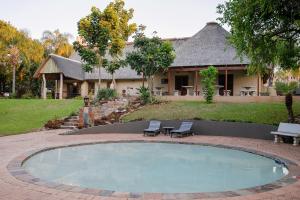 a swimming pool in front of a house at Kruger Whispering Waters in Hazyview