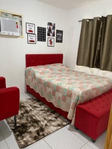 a bedroom with a bed and a red chair at Apartamento Mobiliado para seu conforto in Caruaru